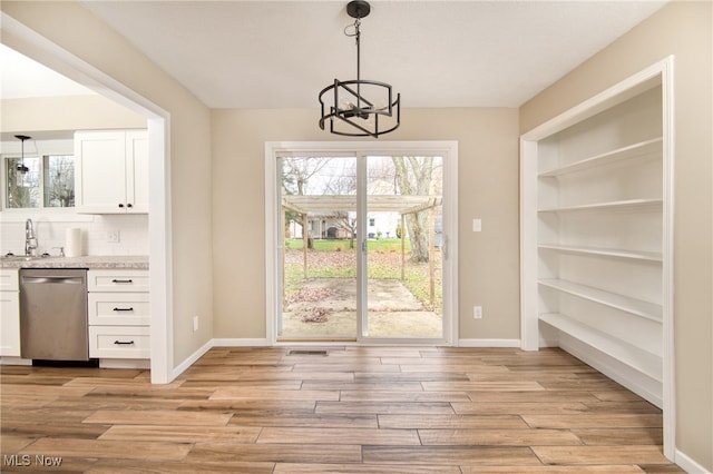 unfurnished dining area featuring a chandelier, sink, and light hardwood / wood-style floors