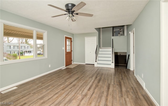 unfurnished living room with dark hardwood / wood-style floors, ceiling fan, and a textured ceiling