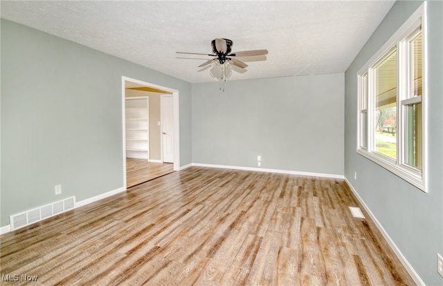 spare room featuring ceiling fan, light hardwood / wood-style floors, and a textured ceiling