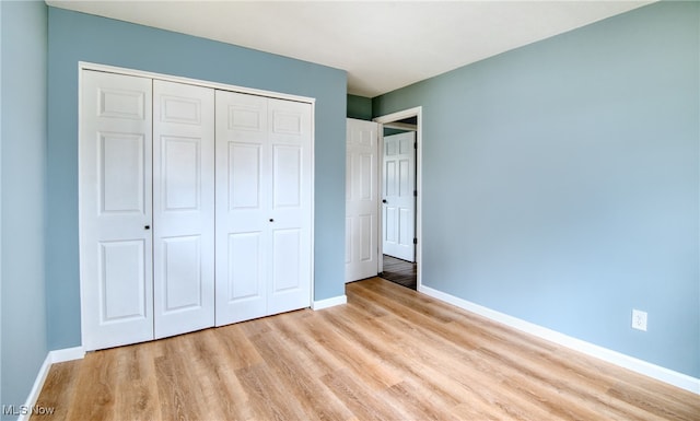 unfurnished bedroom with light wood-type flooring and a closet