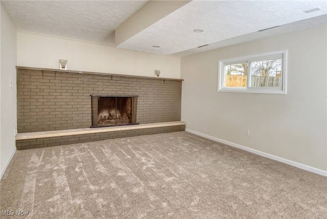 unfurnished living room with carpet, a textured ceiling, and a brick fireplace