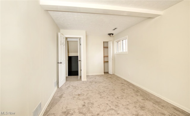 carpeted spare room featuring beamed ceiling and a textured ceiling