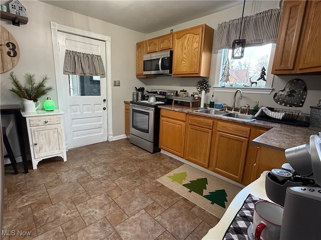 kitchen featuring appliances with stainless steel finishes, hanging light fixtures, and sink