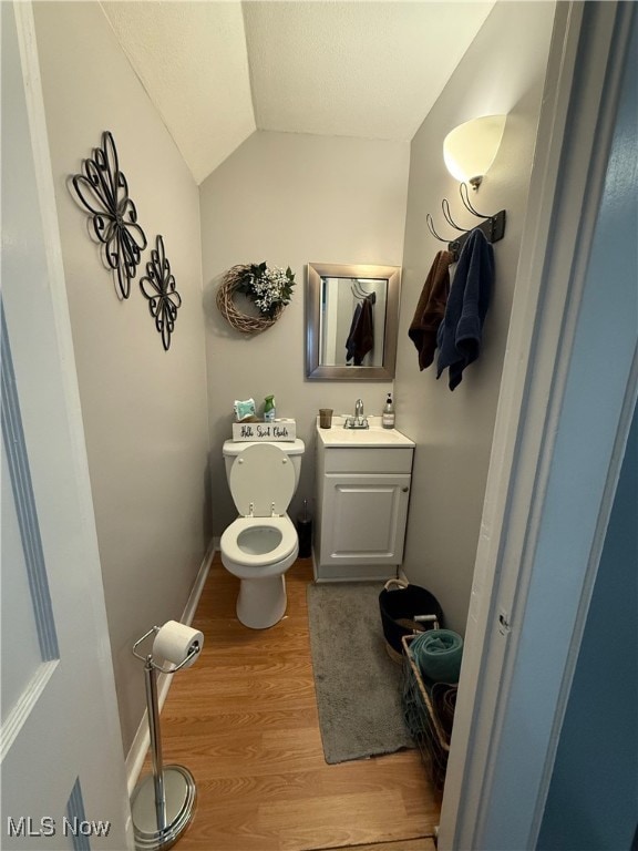 bathroom featuring toilet, vanity, vaulted ceiling, and hardwood / wood-style flooring