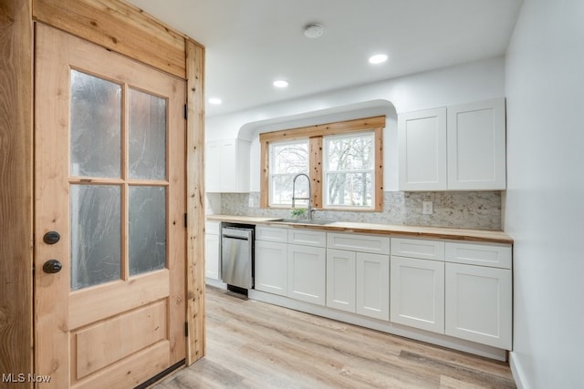 kitchen featuring white cabinetry, sink, dishwasher, light hardwood / wood-style floors, and decorative backsplash