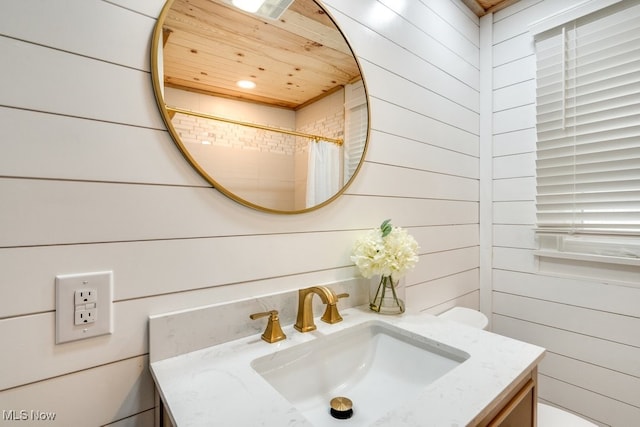 bathroom featuring a shower with curtain, wooden walls, and vanity