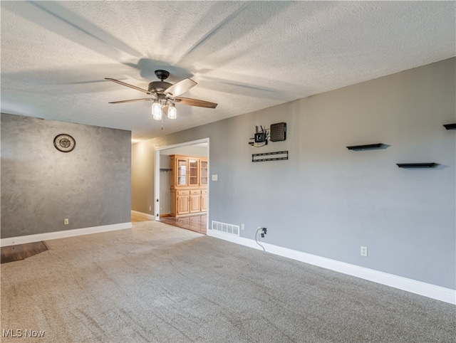 spare room with light carpet, ceiling fan, and a textured ceiling