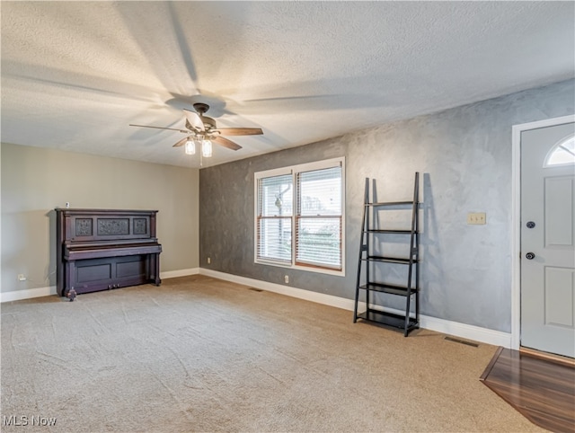 carpeted entryway featuring a textured ceiling and ceiling fan