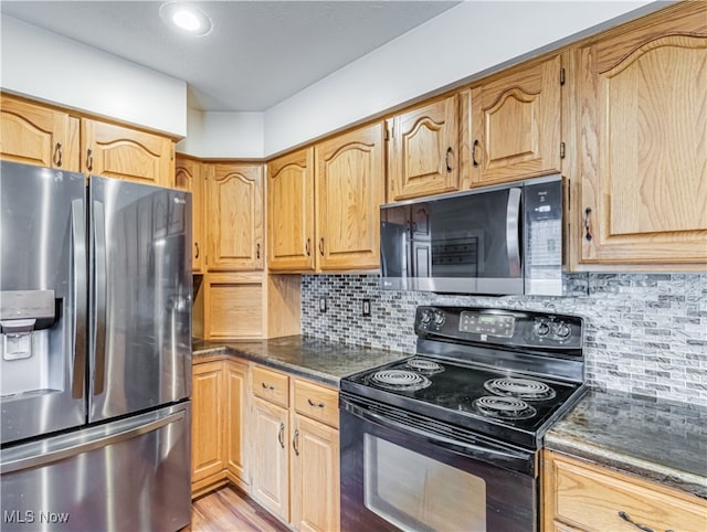 kitchen featuring dark stone counters, decorative backsplash, light hardwood / wood-style floors, and appliances with stainless steel finishes