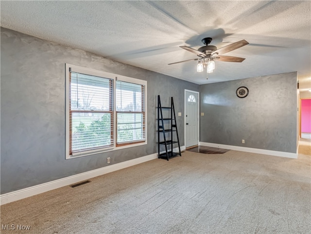 carpeted empty room with ceiling fan and a textured ceiling