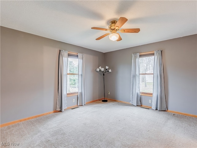 carpeted empty room featuring a wealth of natural light and ceiling fan