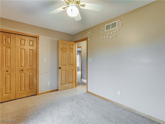 unfurnished bedroom featuring ceiling fan, light colored carpet, and a closet