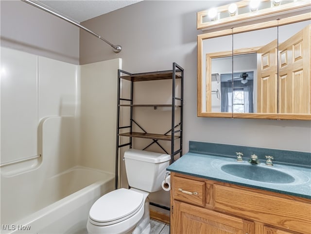 full bathroom with washtub / shower combination, ceiling fan, vanity, and toilet