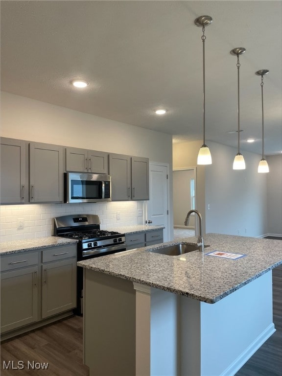 kitchen featuring light stone countertops, sink, a center island with sink, and appliances with stainless steel finishes