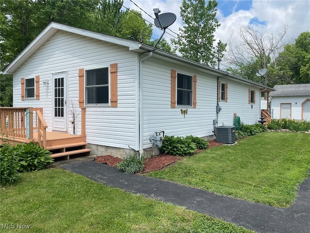 rear view of property featuring central air condition unit, a deck, and a lawn