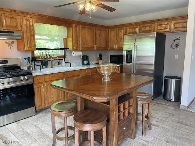 kitchen featuring appliances with stainless steel finishes, light wood-type flooring, ceiling fan, and sink