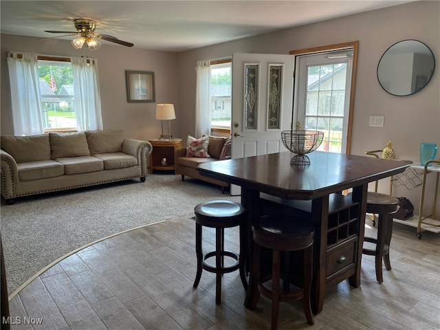 carpeted dining area featuring ceiling fan and plenty of natural light