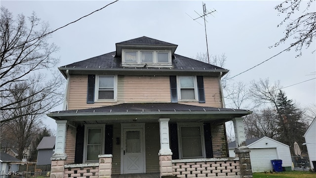 view of front facade with an outbuilding, covered porch, and a garage