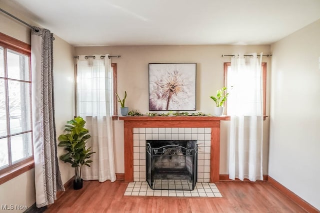 sitting room featuring a tiled fireplace and wood-type flooring