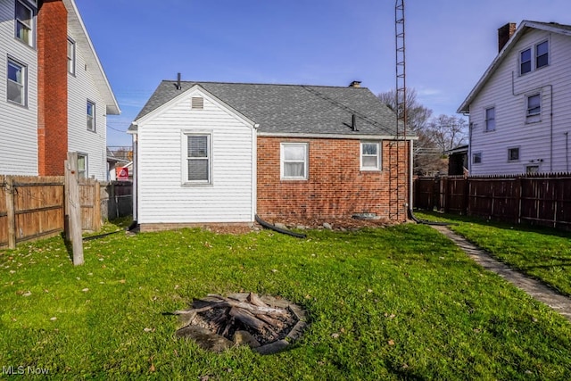 rear view of house featuring a yard and an outdoor fire pit