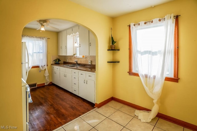 kitchen with backsplash, ceiling fan, sink, light hardwood / wood-style flooring, and white cabinetry