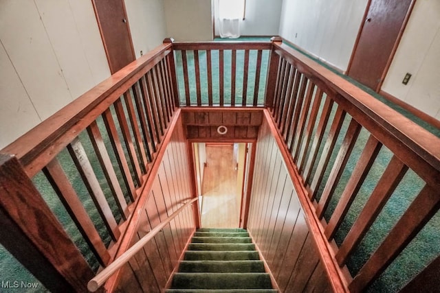 stairway featuring a wealth of natural light and wooden walls