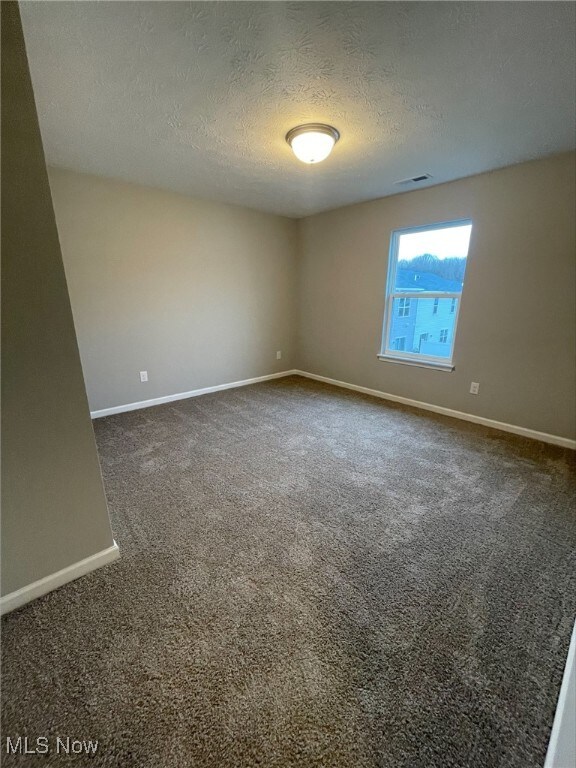 carpeted empty room with a textured ceiling