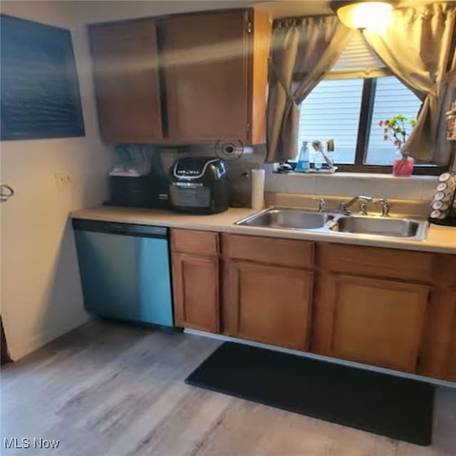 kitchen with light wood-type flooring, stainless steel dishwasher, and sink