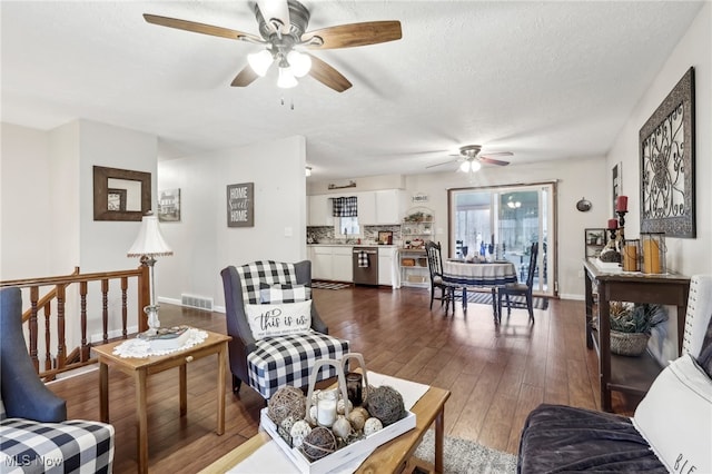 living room with a textured ceiling, dark hardwood / wood-style floors, and ceiling fan