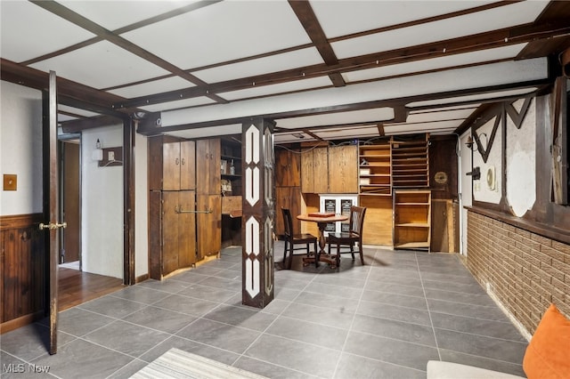 interior space with beam ceiling, dark tile patterned floors, and brick wall