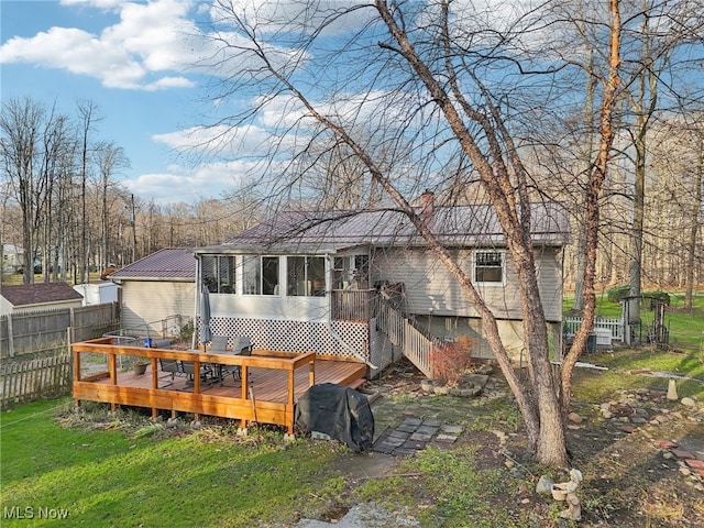 back of house with a yard, a wooden deck, and a sunroom