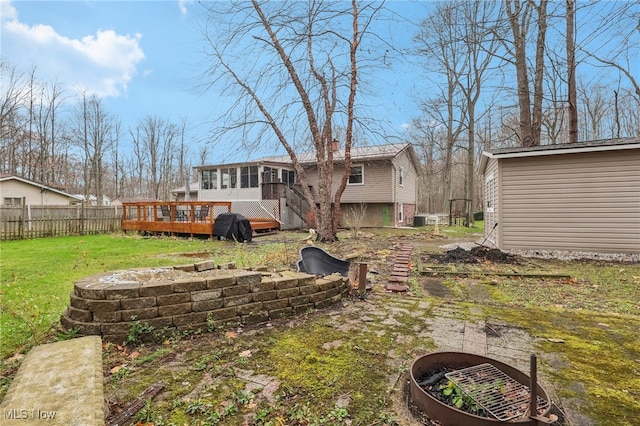 rear view of property featuring a sunroom, a yard, and a deck