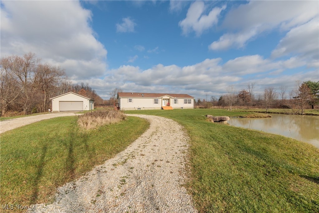 view of front facade featuring a water view, an outbuilding, a garage, and a front lawn