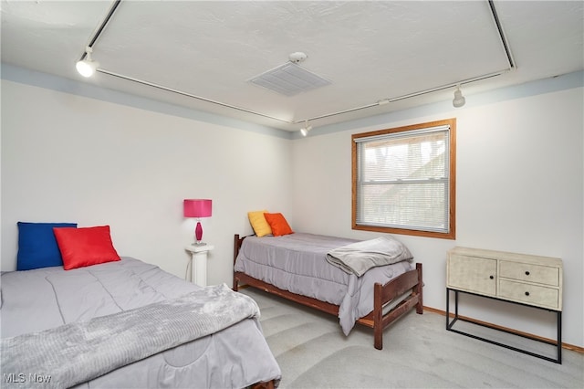 bedroom with light carpet and track lighting