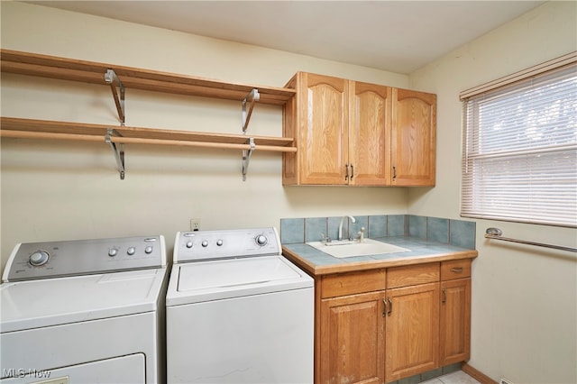 laundry area with washing machine and dryer, sink, and cabinets