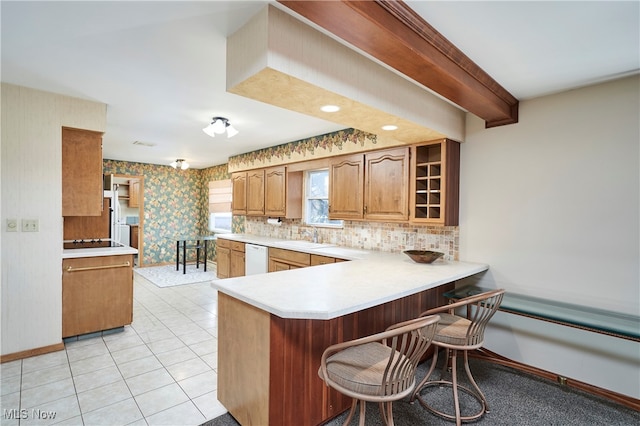 kitchen featuring white dishwasher, sink, light tile patterned flooring, kitchen peninsula, and a breakfast bar area