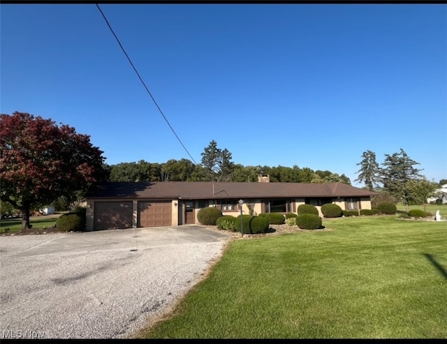 single story home with a garage and a front lawn