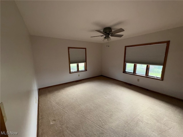 spare room featuring carpet flooring, ceiling fan, and a healthy amount of sunlight