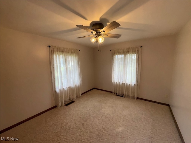 unfurnished room with ceiling fan, light carpet, and a wealth of natural light