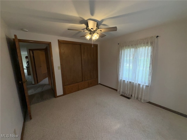 unfurnished bedroom with ceiling fan, light carpet, and a closet