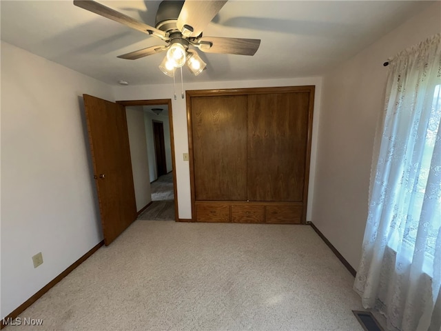 unfurnished bedroom with ceiling fan, light colored carpet, and a closet