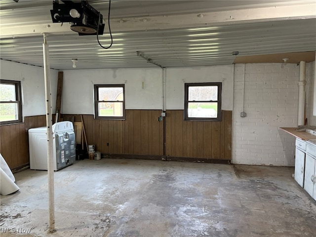 garage with washer / clothes dryer, wood walls, and a garage door opener