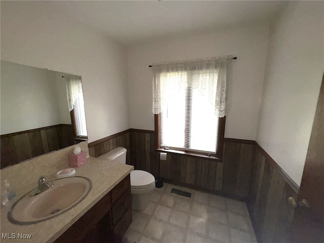 bathroom featuring wood walls, vanity, and toilet