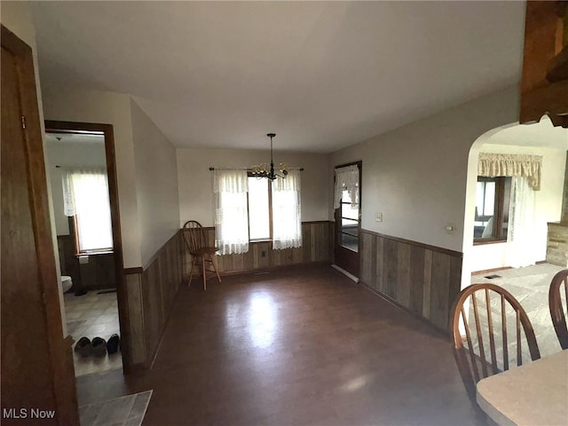 dining space with concrete flooring, wooden walls, and a notable chandelier