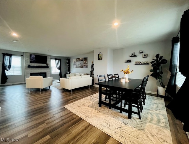 dining room featuring wood-type flooring and a brick fireplace