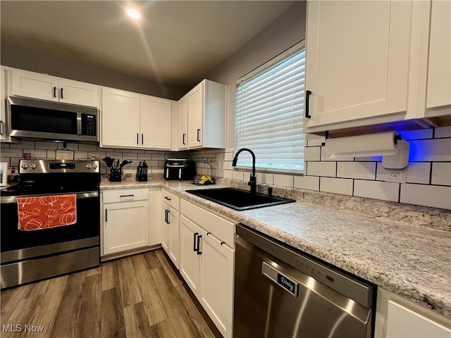 kitchen with sink, dark hardwood / wood-style floors, backsplash, white cabinets, and appliances with stainless steel finishes