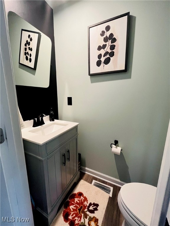 bathroom featuring hardwood / wood-style flooring, vanity, and toilet