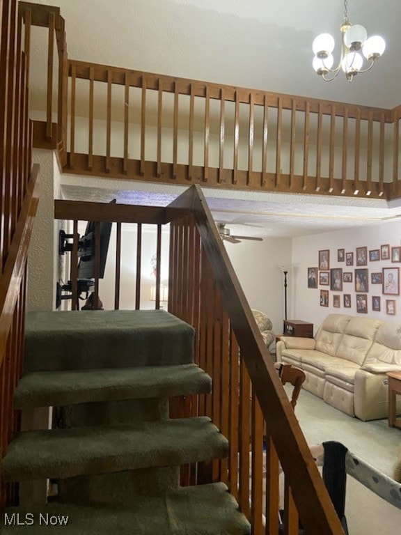 stairway featuring ceiling fan with notable chandelier and carpet floors