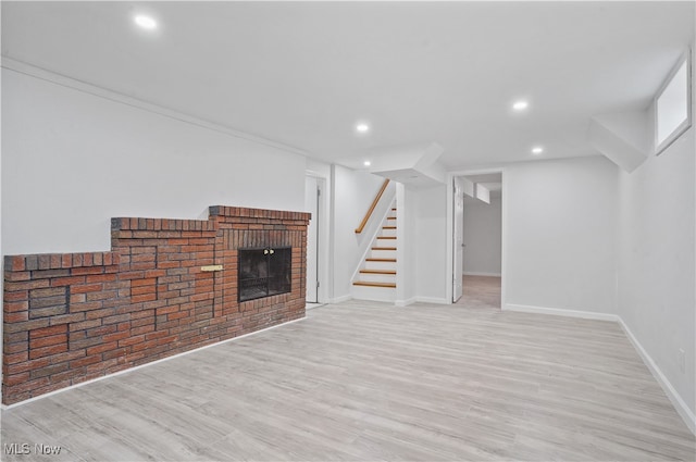 unfurnished living room featuring a brick fireplace, light hardwood / wood-style flooring, and ornamental molding