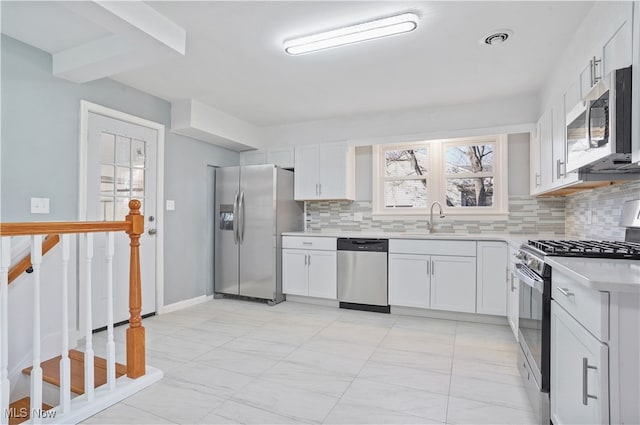 kitchen with white cabinets, decorative backsplash, sink, and appliances with stainless steel finishes